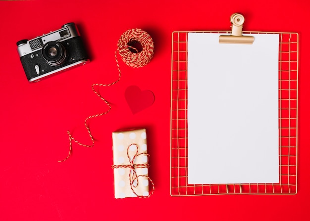 Flat lay of photo camera and blank paper