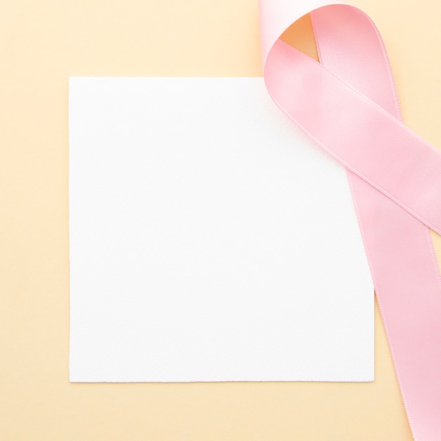 Flat lay piece of paper with pink ribbon