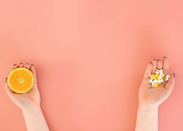 Flat lay pills and an orange in female hands