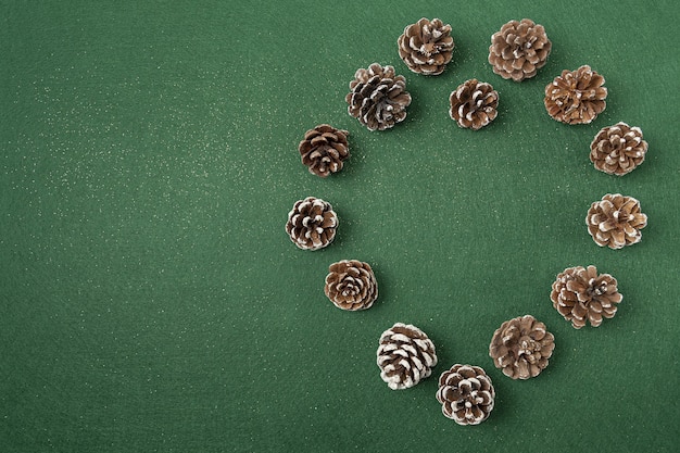 Flat lay of pinecone Christmas decorations on a green surface