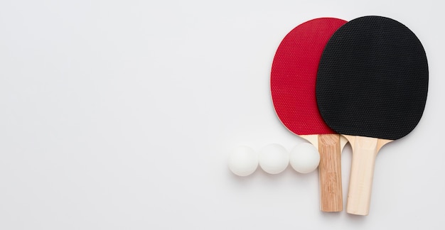 Free photo flat lay of ping pong balls with paddles and copy space