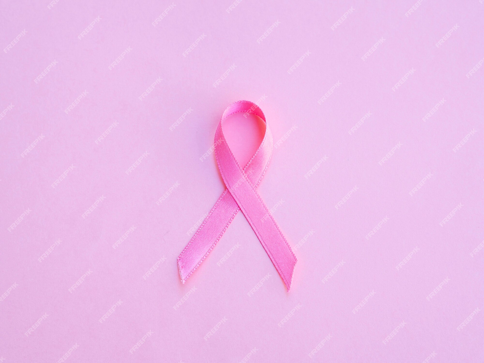 Flat-lay Image Of Three Pink Ribbons Against Coral Background As