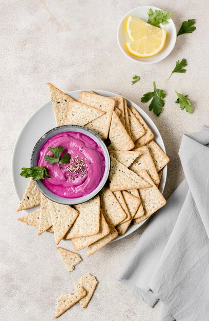 Flat lay of pink sauce with crackers and lemon slices