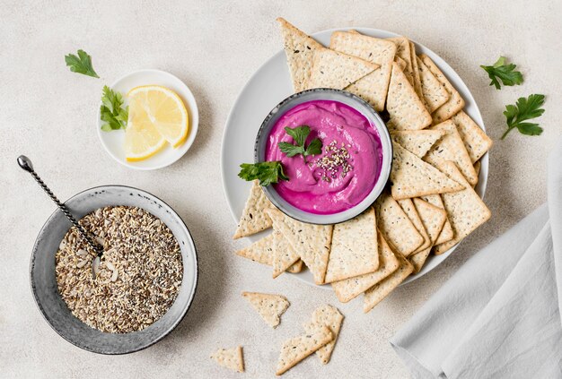 Flat lay of pink sauce with crackers and lemon