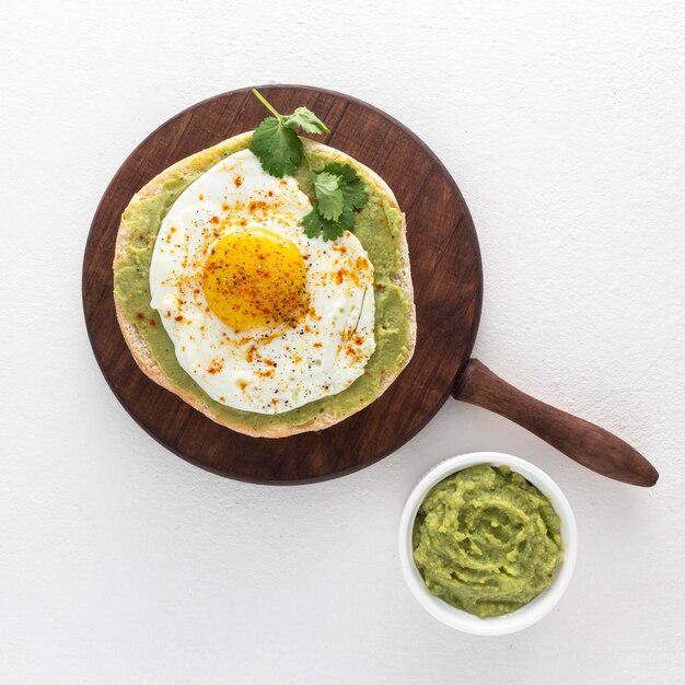 Flat lay pita with avocado spread and fried egg on cutting board