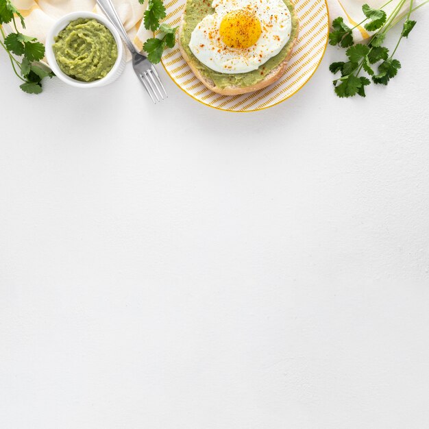 Плоский лаваш с авокадо и жареным яйцом на тарелке с копией пространства