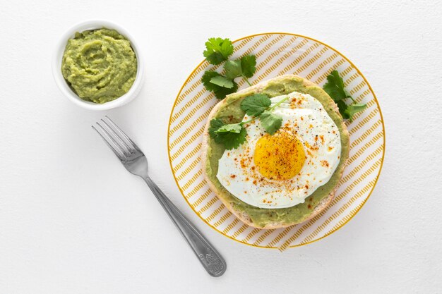 Flat lay pita with avocado spread and fried egg on plate with fork