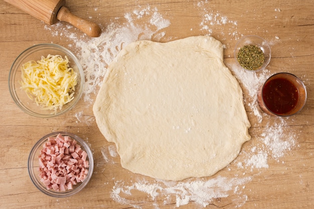 Flat lay pizza dough with tomato sauce mozzarella and ham