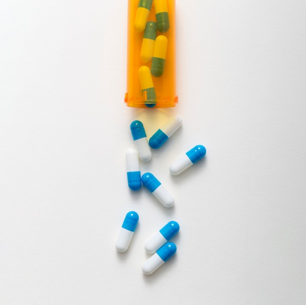 Free photo flat lay of plastic container with pills coming out of it