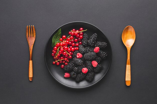 Плоская тарелка ягод с ложкой и вилкой