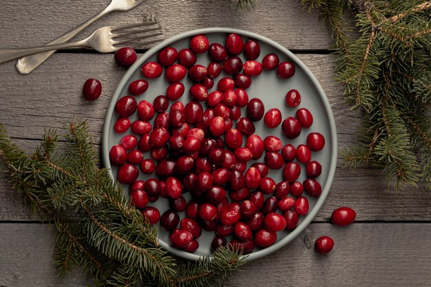 Flat lay of plate of cranberries with pine and forks