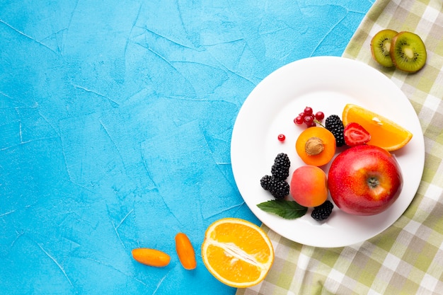 Плоская тарелка свежих ягод и фруктов с copyspace