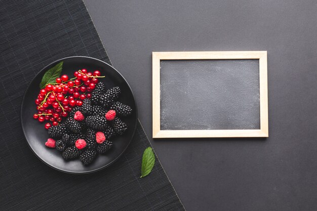 Плоская тарелка свежих ягод с доской