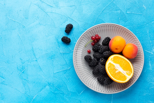 Flat-lay plate of fruits and berries with copyspace
