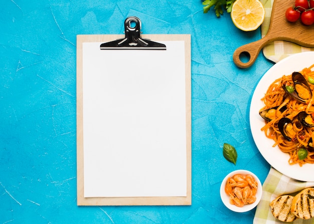 Flat-lay plate of mussels pasta with clipboard