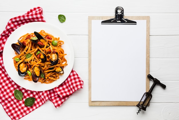 Free photo flat-lay plate of mussels pasta with clipboard