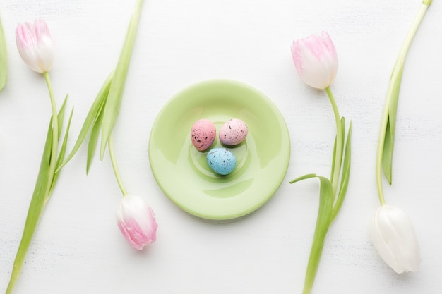 Free photo flat lay of plate with colorful easter eggs and beautiful tulips