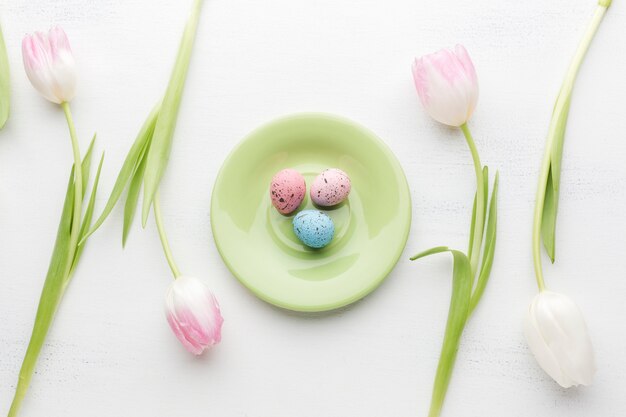 Flat lay of plate with colorful easter eggs and beautiful tulips