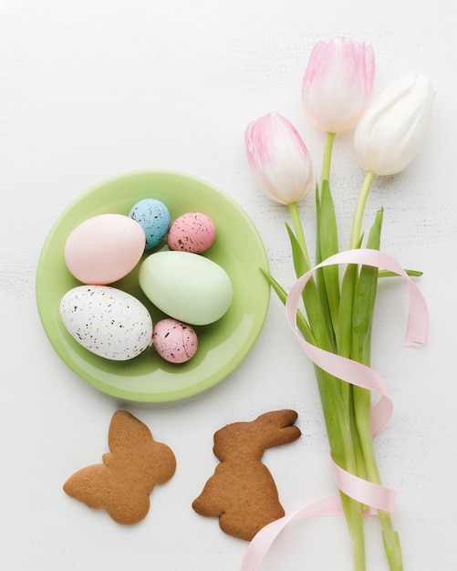 Flat lay of plate with colorful easter eggs and cookies