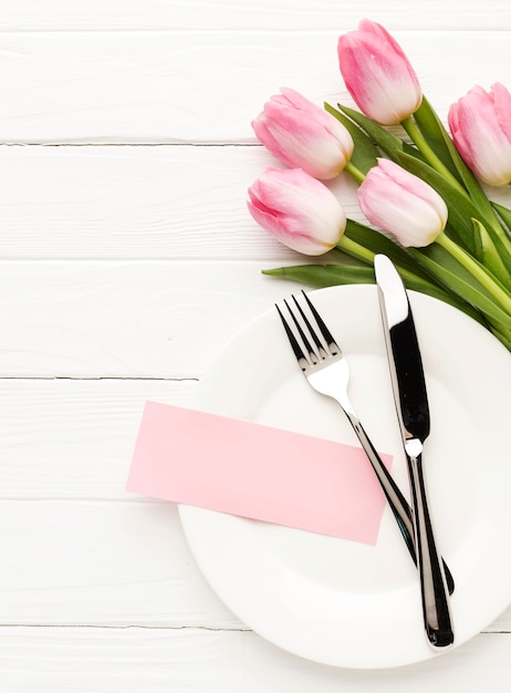 Flat lay plate with cutlery and tulips beside