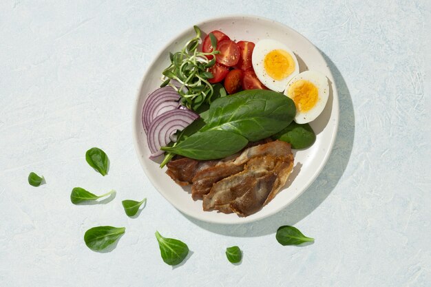 Flat lay of plate with keto diet food and spinach leaves