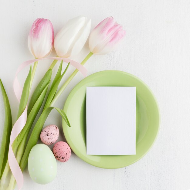 Flat lay of plate with piece of paper and tulips