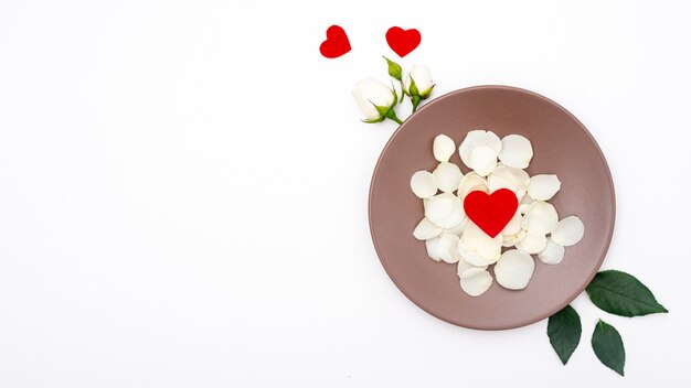 Free photo flat lay of plate with rose petals and hearts