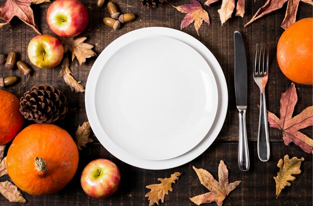Flat lay of plates for thanksgiving dinner with autumn leaves