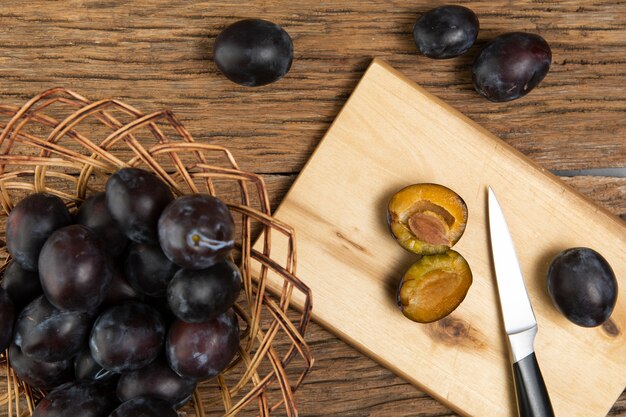 Flat lay of plums on chopper on wooden table