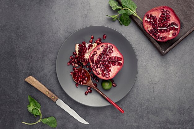 Flat lay of pomegranate on plate with mint and knife