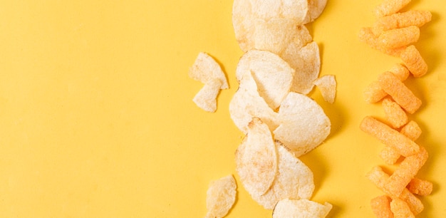 Flat lay of potato chips and cheesy puffs with copy space