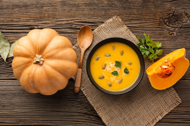 Flat lay pumpkin soup in bowl with pumpkin