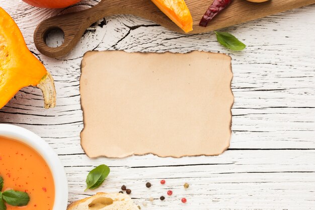 Flat lay pumpkin soup and burnt blank paper