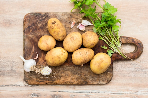 Flat lay raw potatoes on wooden board