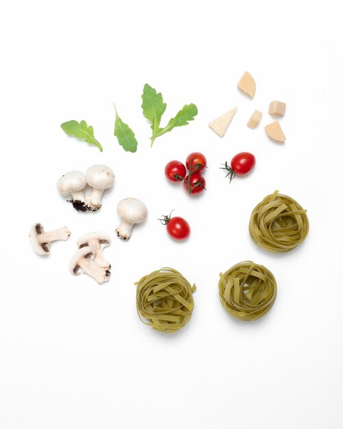 Flat lay of raw tomato pasta ingredients on white surface