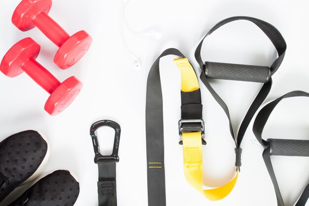 Flat lay of red dumbbells, black sneakers and sport equipment on white background. Sport wear, Sport accessories, top view