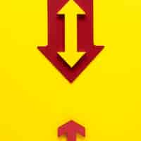 Free photo flat lay red and yellow arrows on yellow background