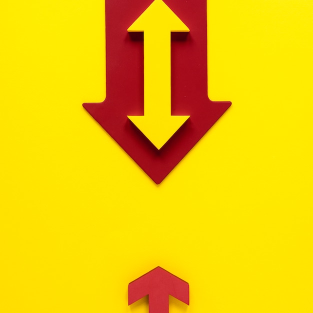 Flat lay red and yellow arrows on yellow background