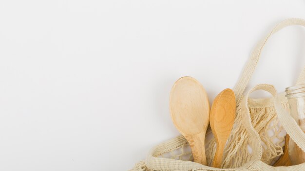 Flat lay of reusable bag with wooden spoons and copy space