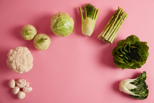 Flat lay of ripe green leafy vegetables containing much vitamins and nutrients. Mushrooms, broccoli, fennel, asparagus, bok choy arranged in half circle. Organic eating, healthy diet concept.