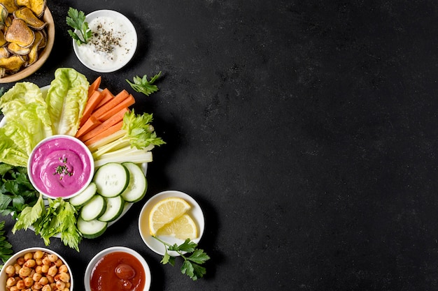 Flat lay of roasted potatoes in bowl with vegetables and copy space