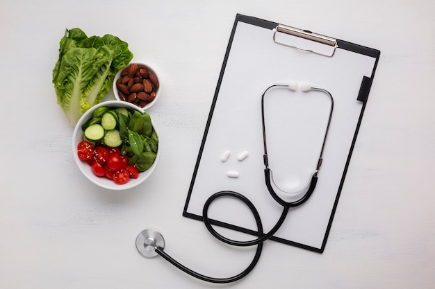 Free photo flat lay of salad bowl and stethoscope