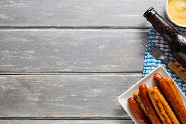 Flat lay of sausages with beer bottle and copy space