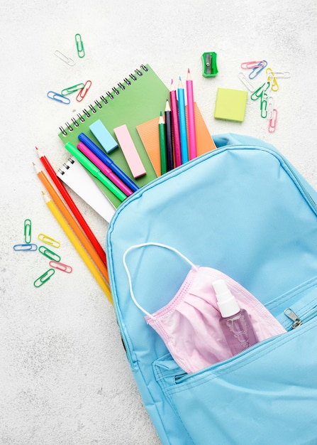 Flat lay of school essentials with backpack and medical mask