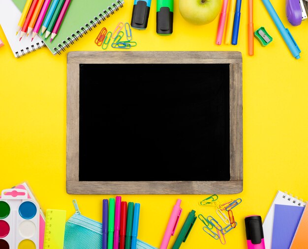 Flat lay of school essentials with blackboard and apple