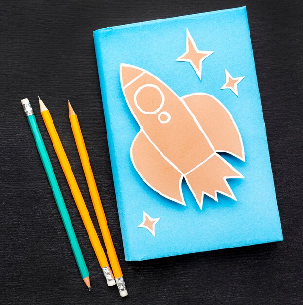 Плоская планировка школьных принадлежностей с книгой и карандашами