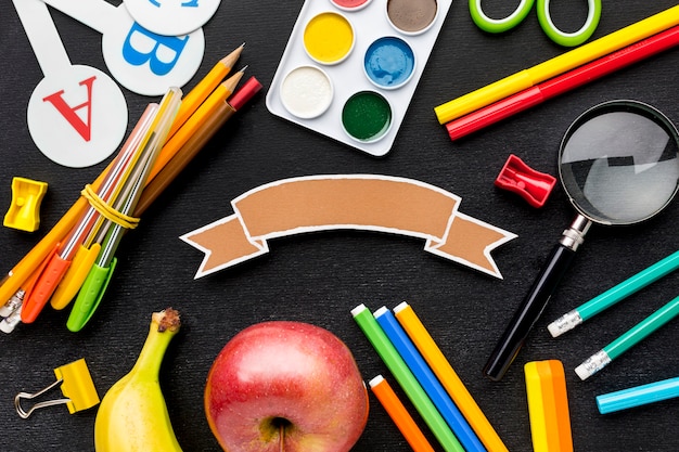 Flat lay of school essentials with fruit and pencils