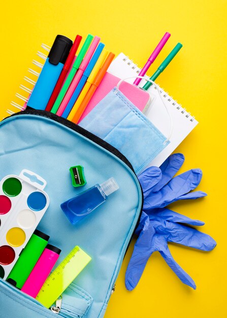 Flat lay of school essentials with gloves and backpack