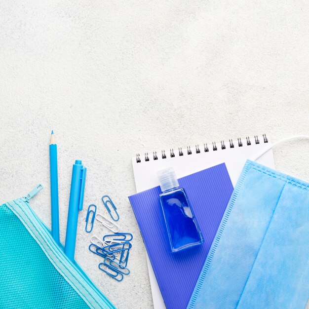 Flat lay of school essentials with medical mask and paper clips