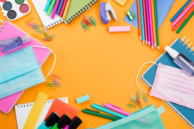 Плоская планировка школьных принадлежностей с медицинскими масками и цветными карандашами